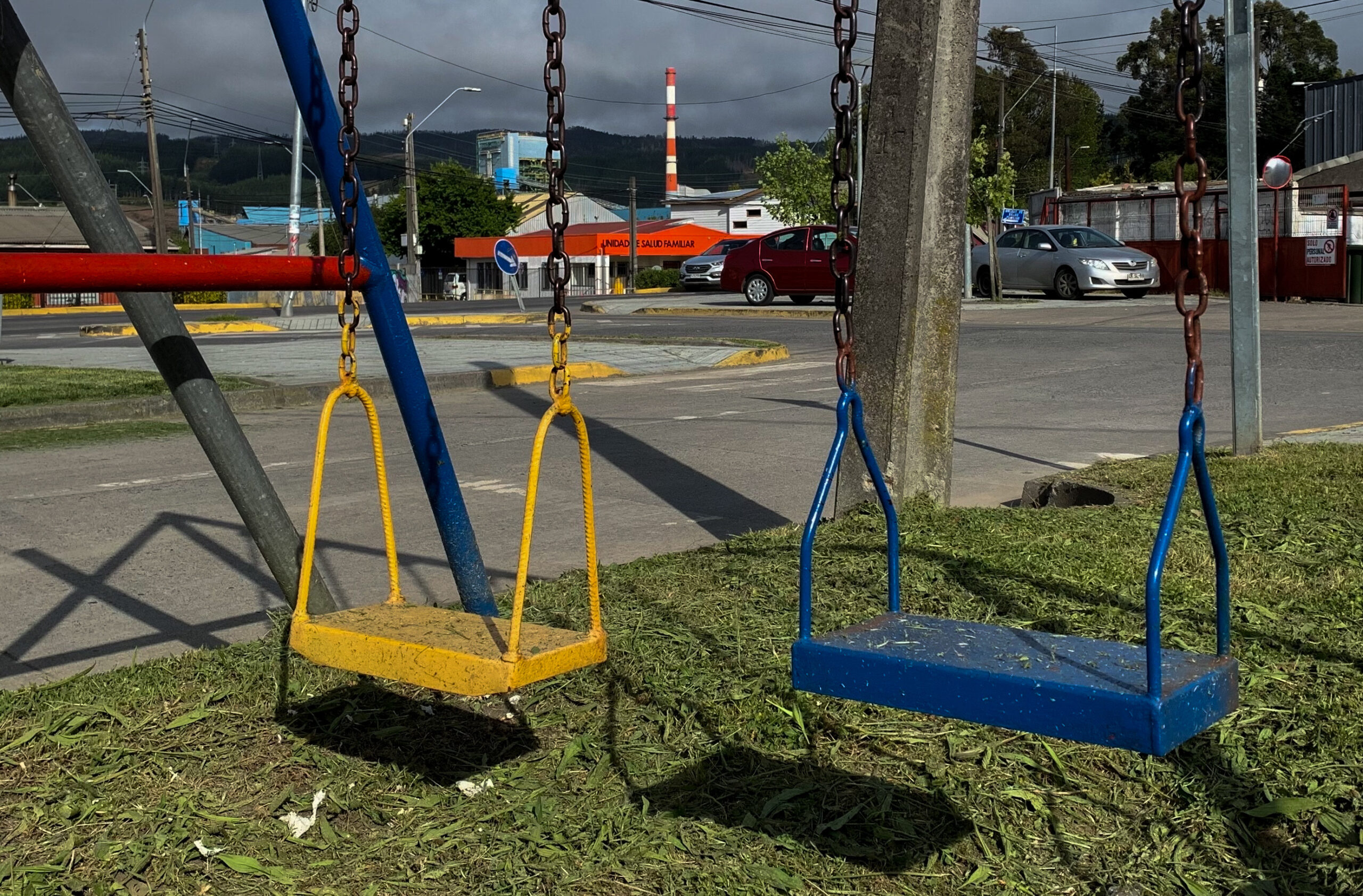 Columpios en un parque de Coronel con la Termoeléctrica Santa María de fondo